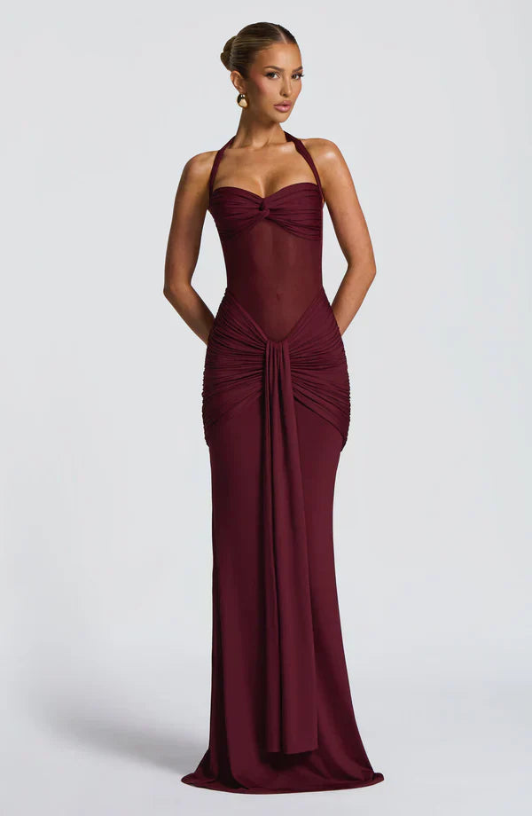 Front view of a burgundy Victoria ruched maxi dress with halter neckline and sheer midriff detail, elegant evening dress.