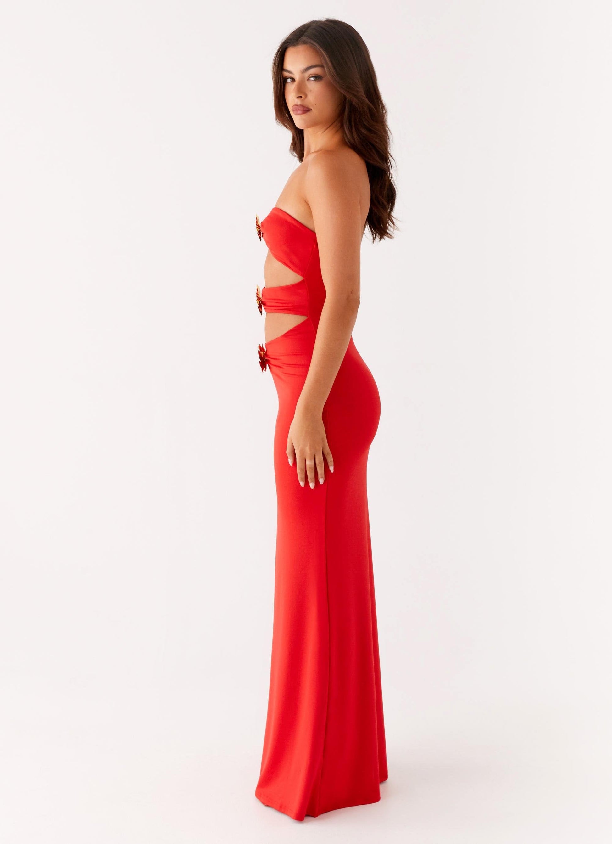 Side profile of the red Vienna Cutout Maxi Dress, showcasing the form-fitting silhouette and waist cutouts.
