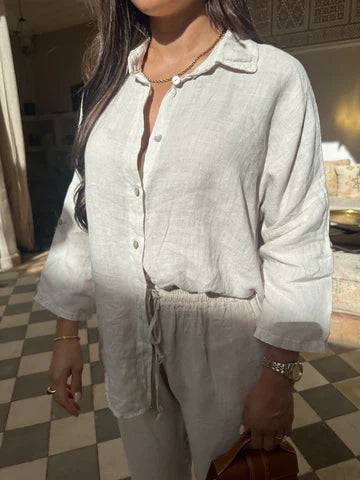 Viviana two-piece linen set in off-white linen, showing the button-down shirt with rolled sleeves and drawstring waist pants, accessorized with a gold chain necklace.