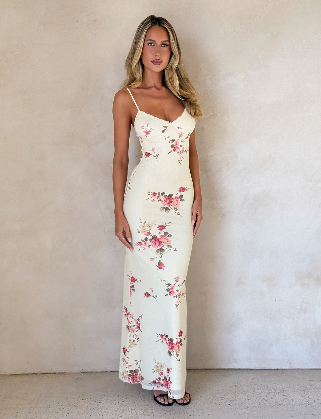 Full-length view of a cream floral maxi dress with pink and red roses, featuring delicate spaghetti straps and a fitted silhouette.