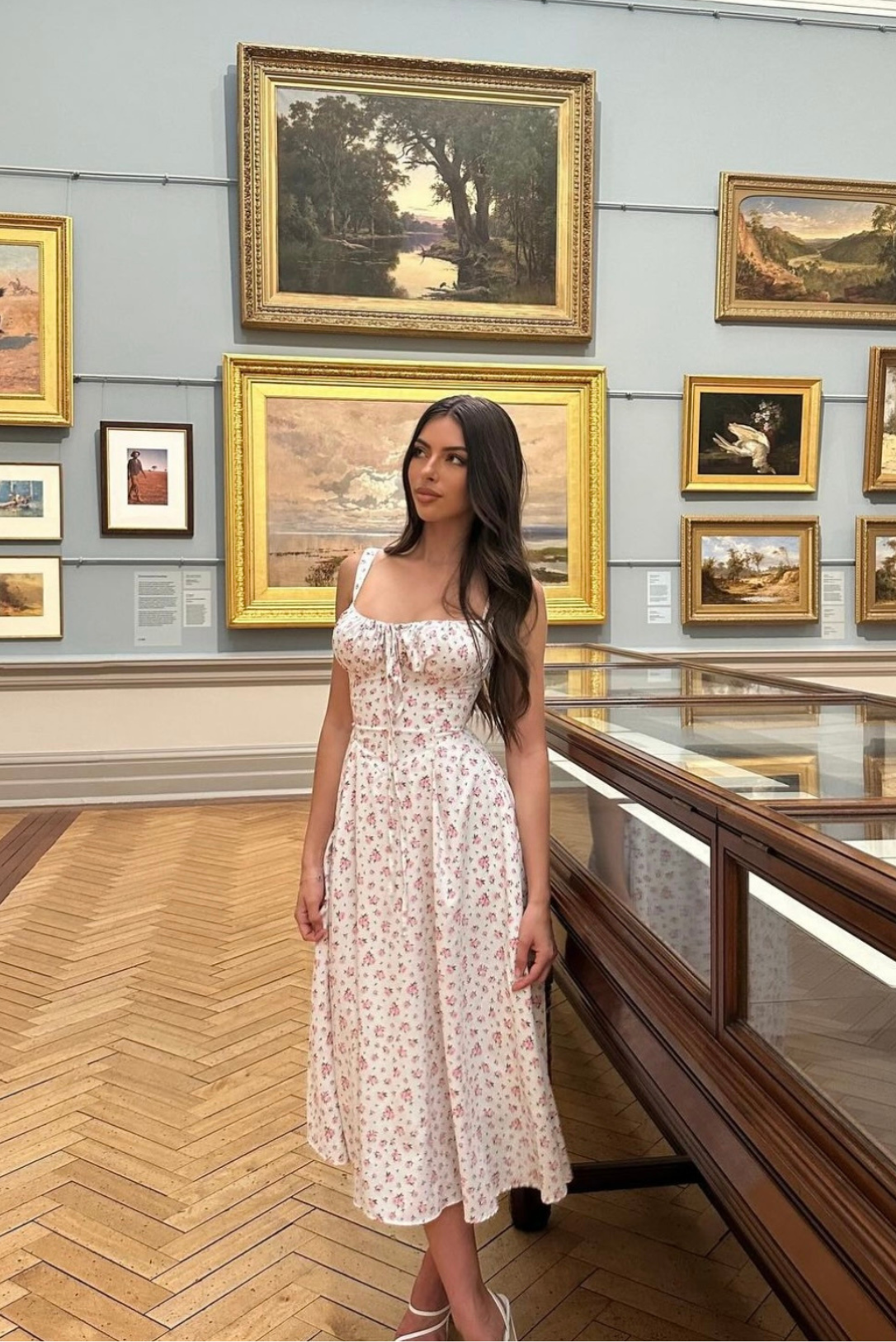 Side profile of a woman wearing a white floral midi dress with a sweetheart neckline and thin straps.