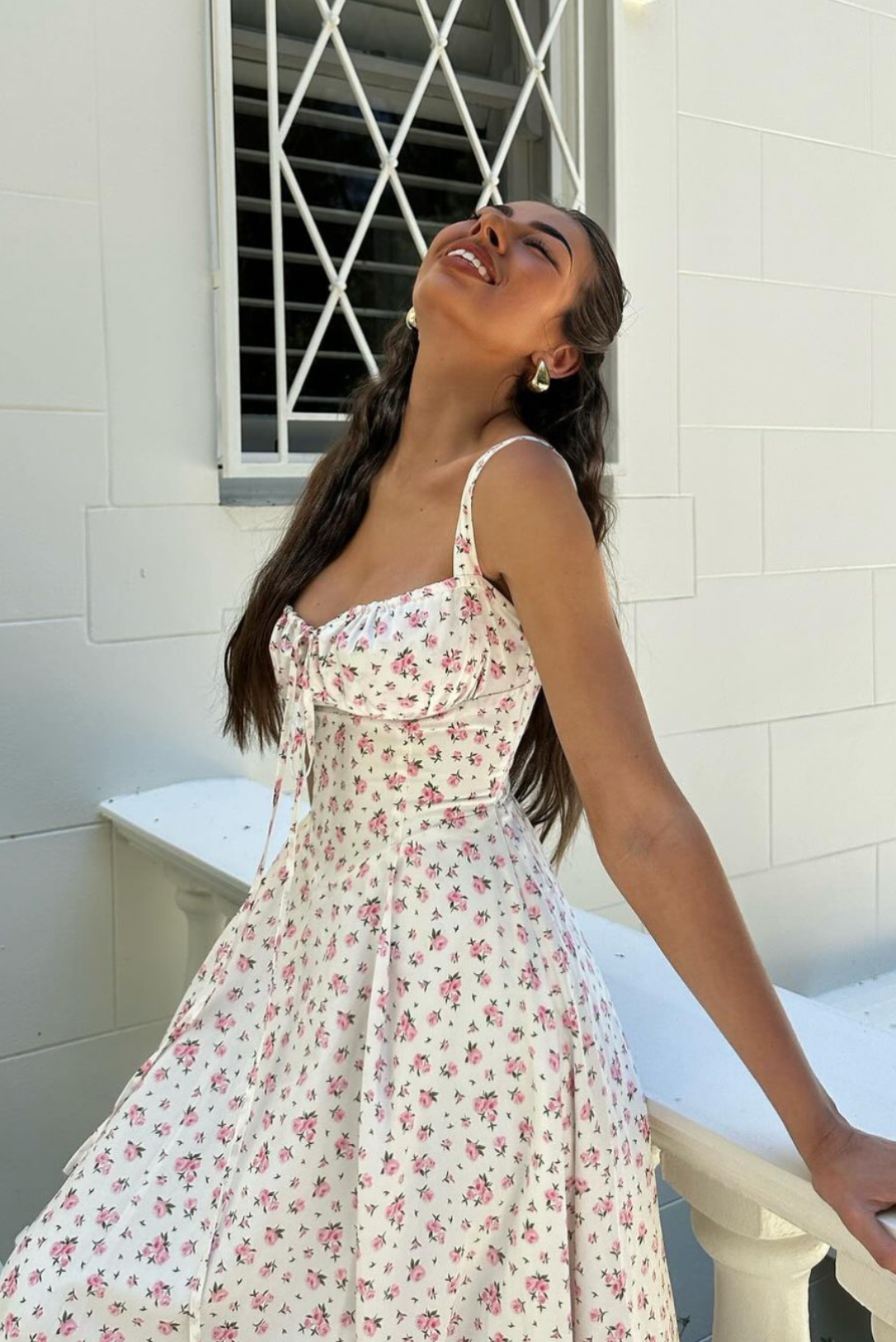 Close-up of a white floral midi dress featuring a ruched bodice and delicate pink flower pattern.