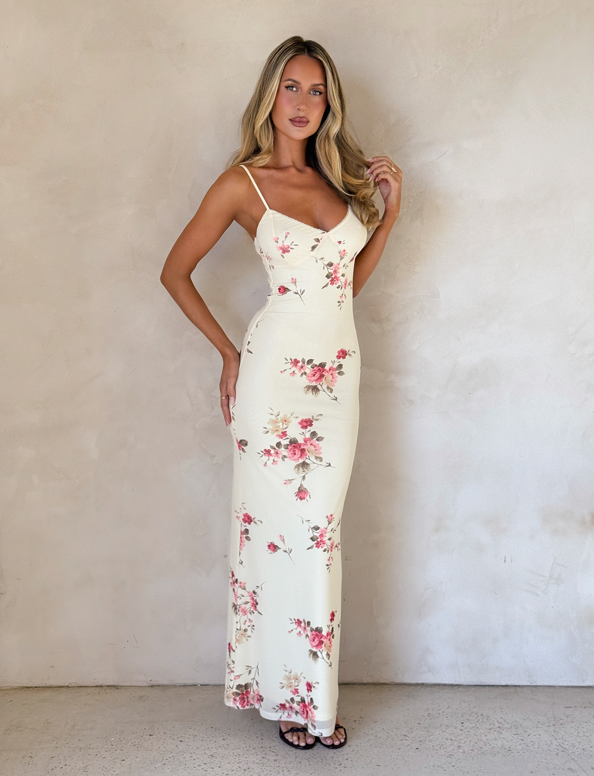 Yellow floral maxi dress with spaghetti straps and body-hugging cut — styled with black heels.